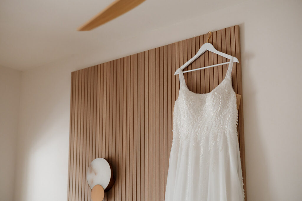 Close-up of bridal gown buttons being fastened during wedding morning preparations
