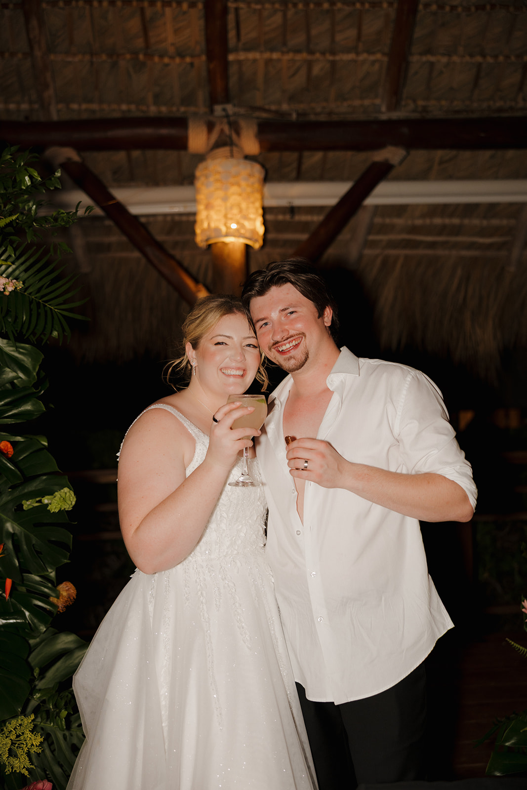 Newlywed couple holding cocktails and smiling during their beach wedding reception in Florida
