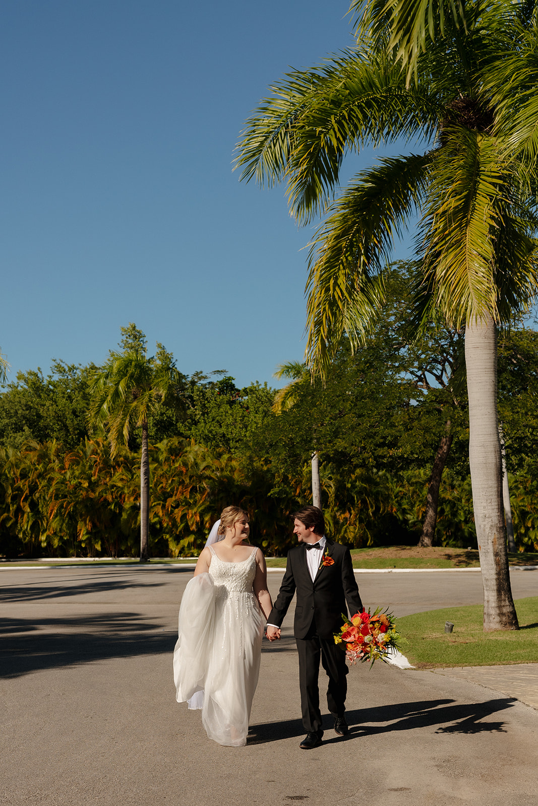 Newly married couple walking beneath palm trees after their wedding in Florida