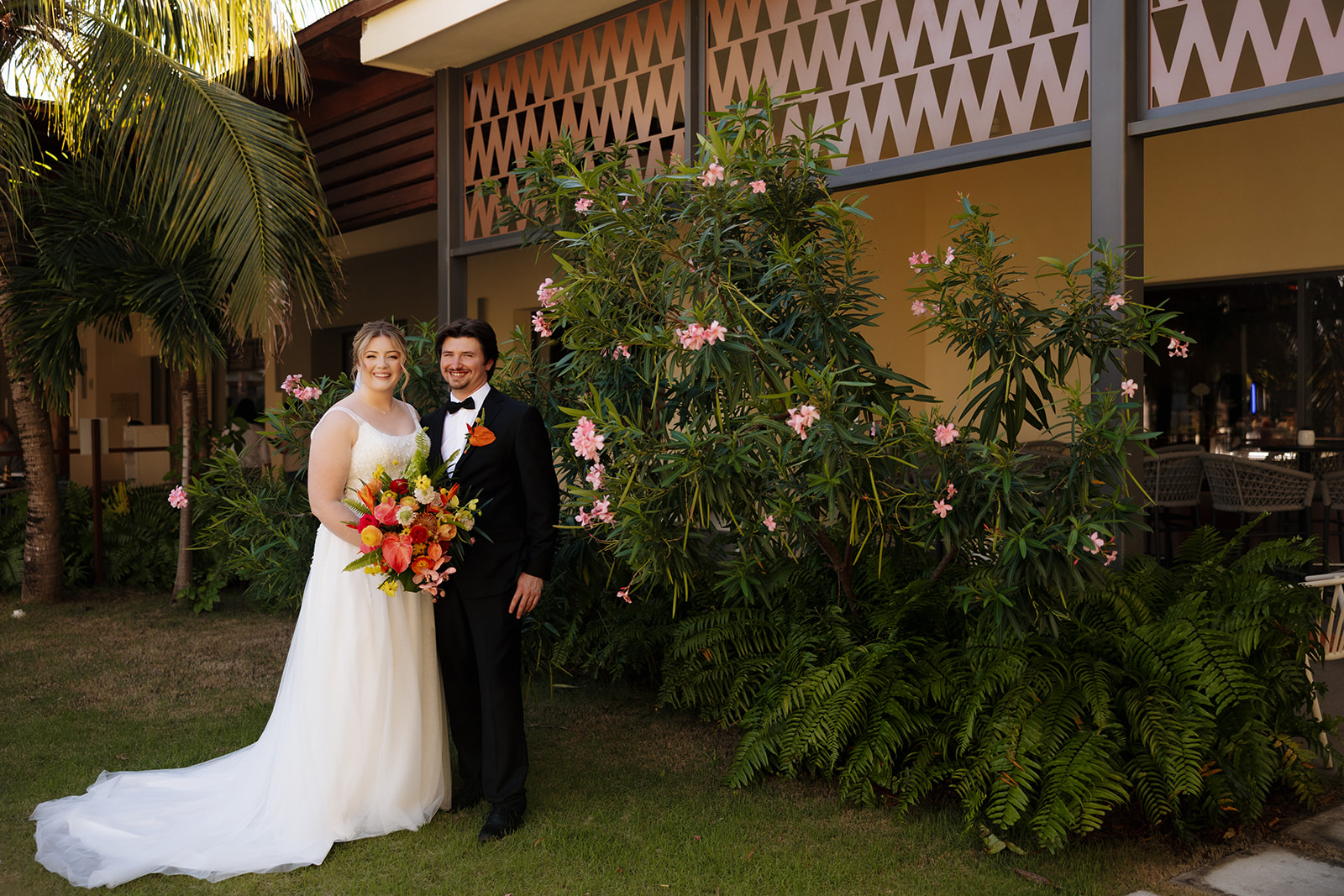 Bride and groom posing together in tropical garden outside their Florida wedding venue