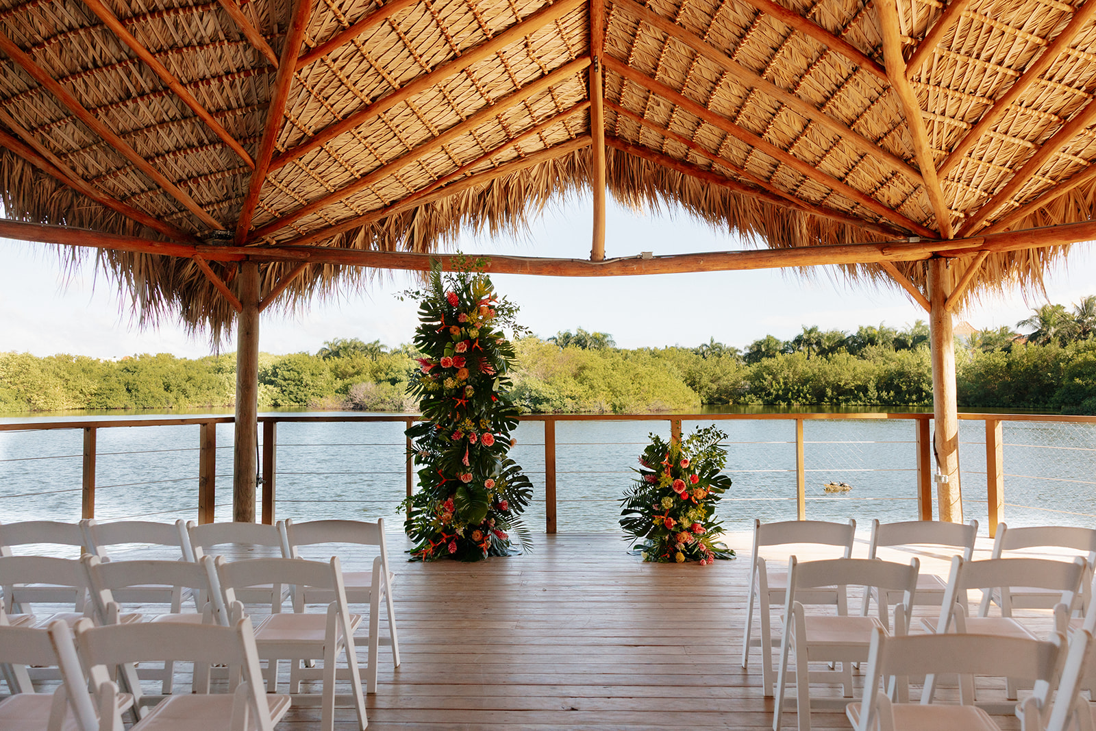 Outdoor ceremony setup with tropical florals and waterfront views for a beach wedding
