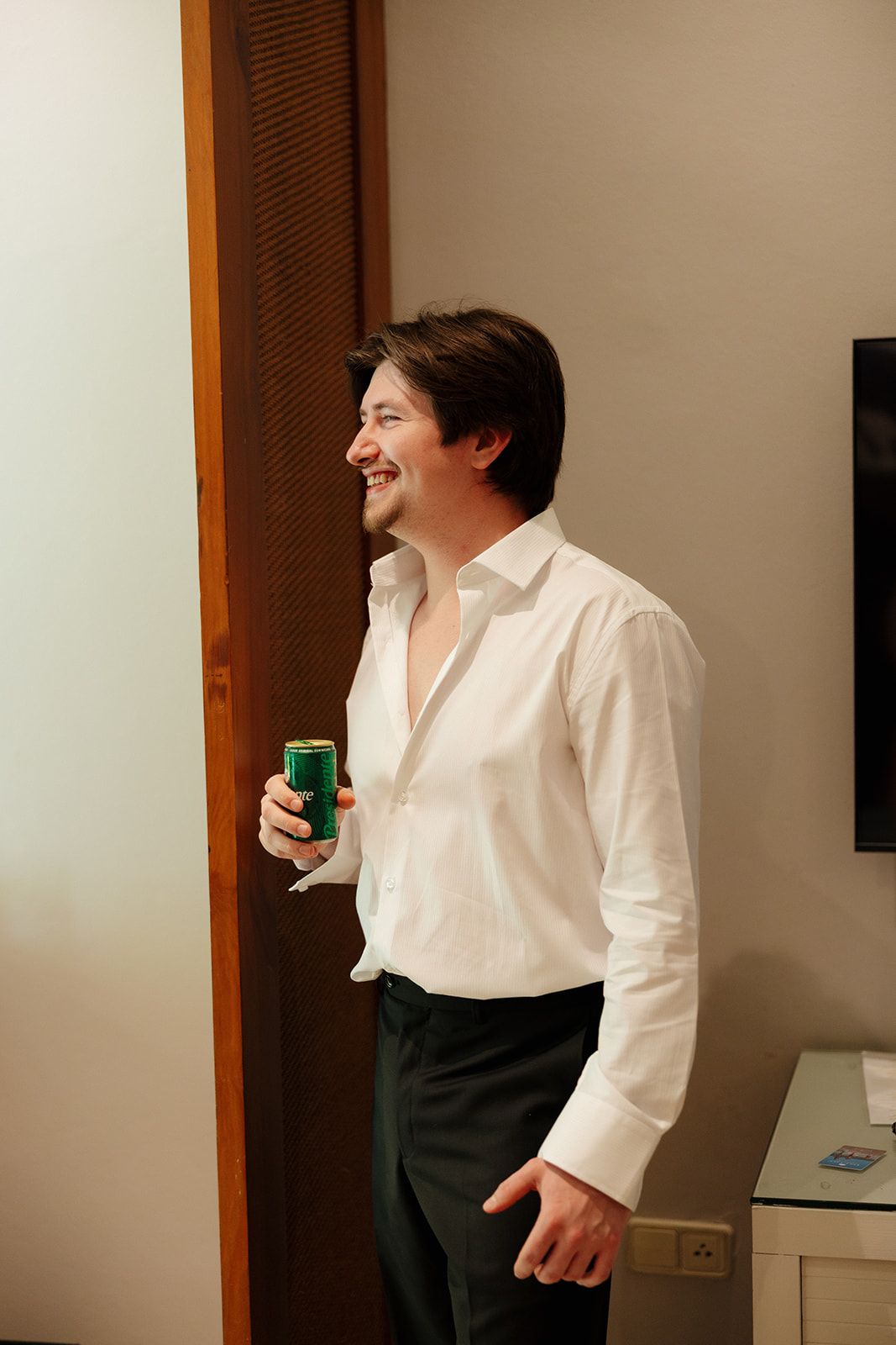 Groom smiling while getting ready with drink before the wedding ceremony