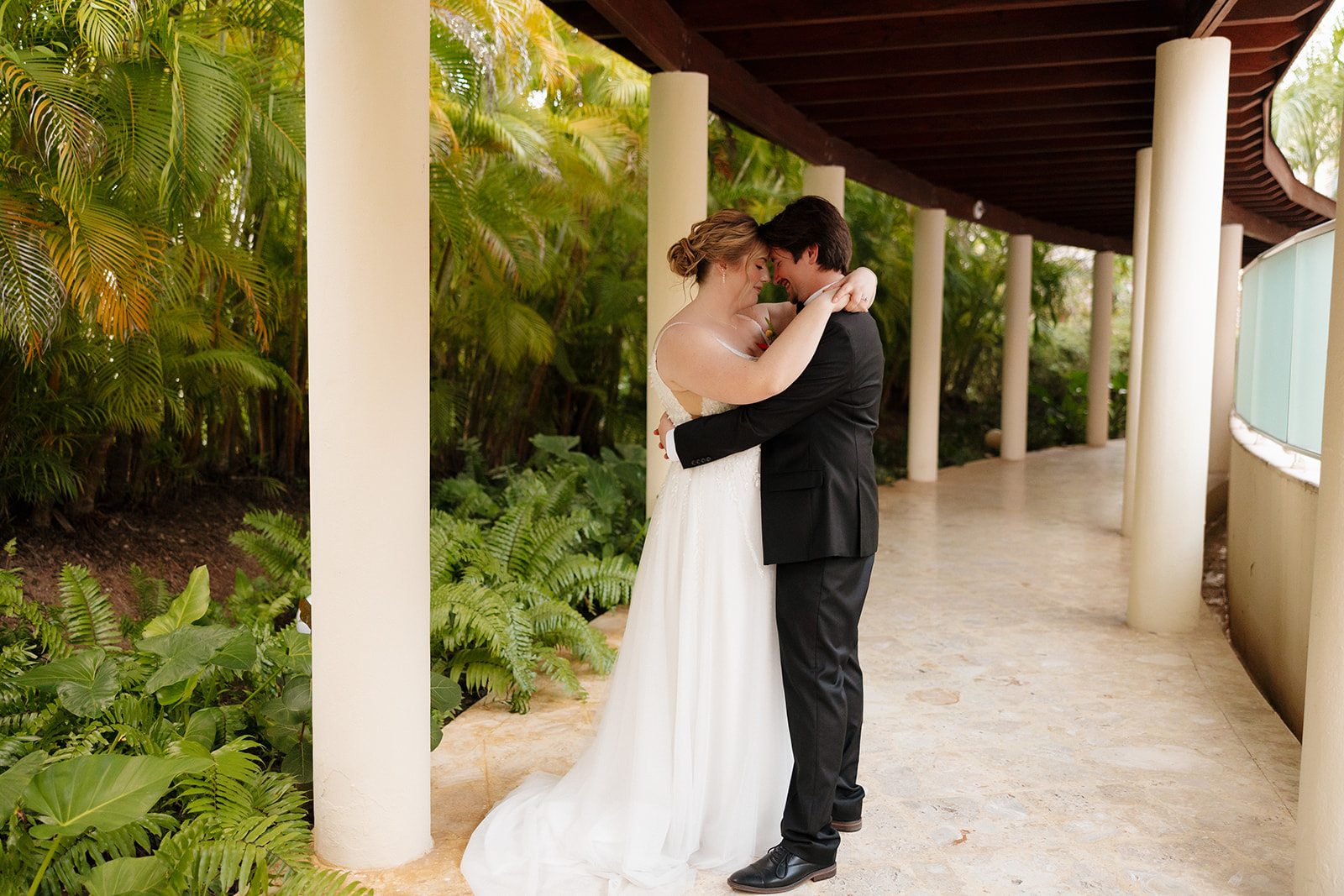 Bride and groom embracing beneath palm trees during sunset portraits at a Florida beach wedding
