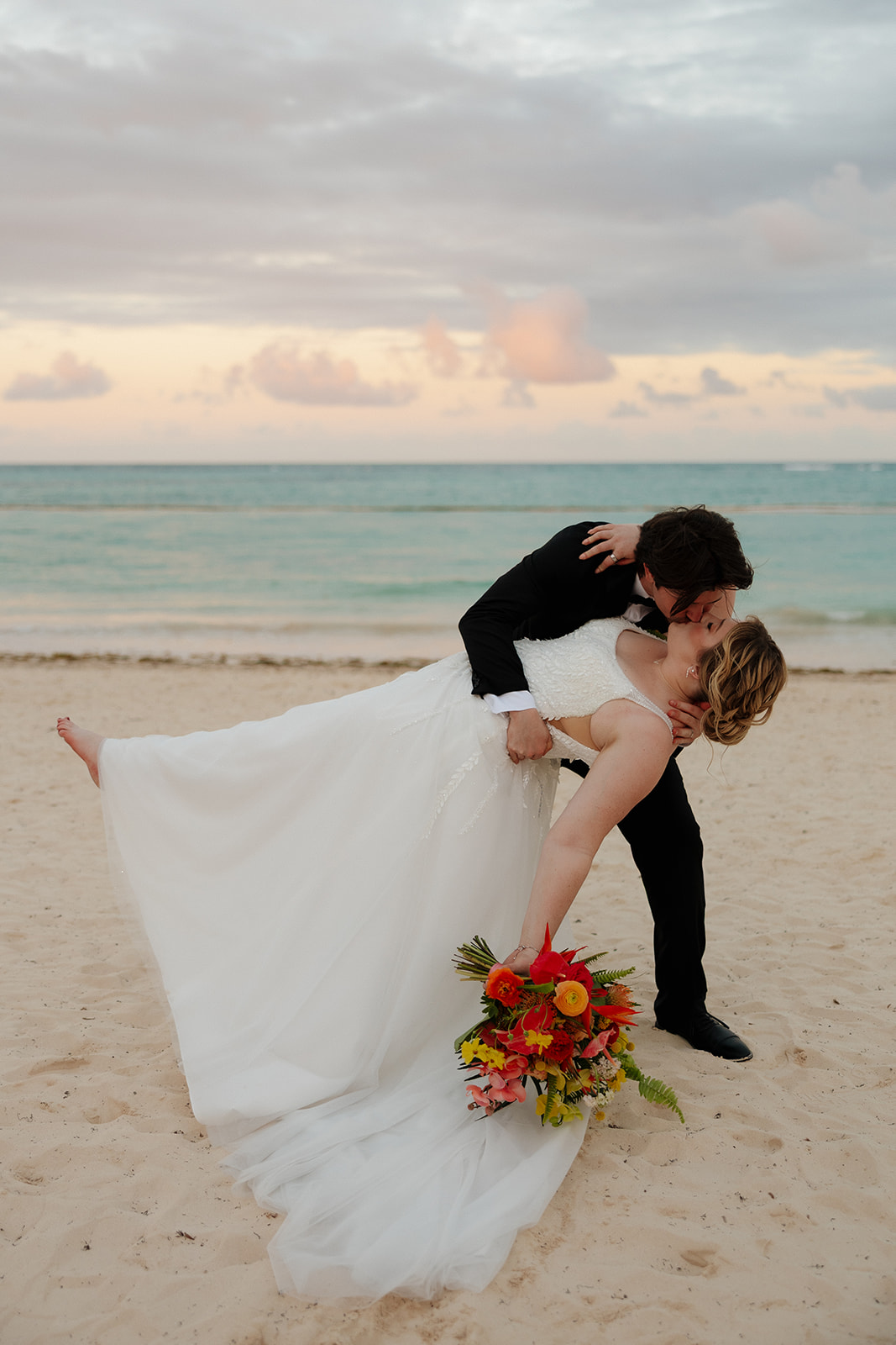 Bride and groom sharing a romantic dip kiss during sunset portraits at a Florida beach wedding
