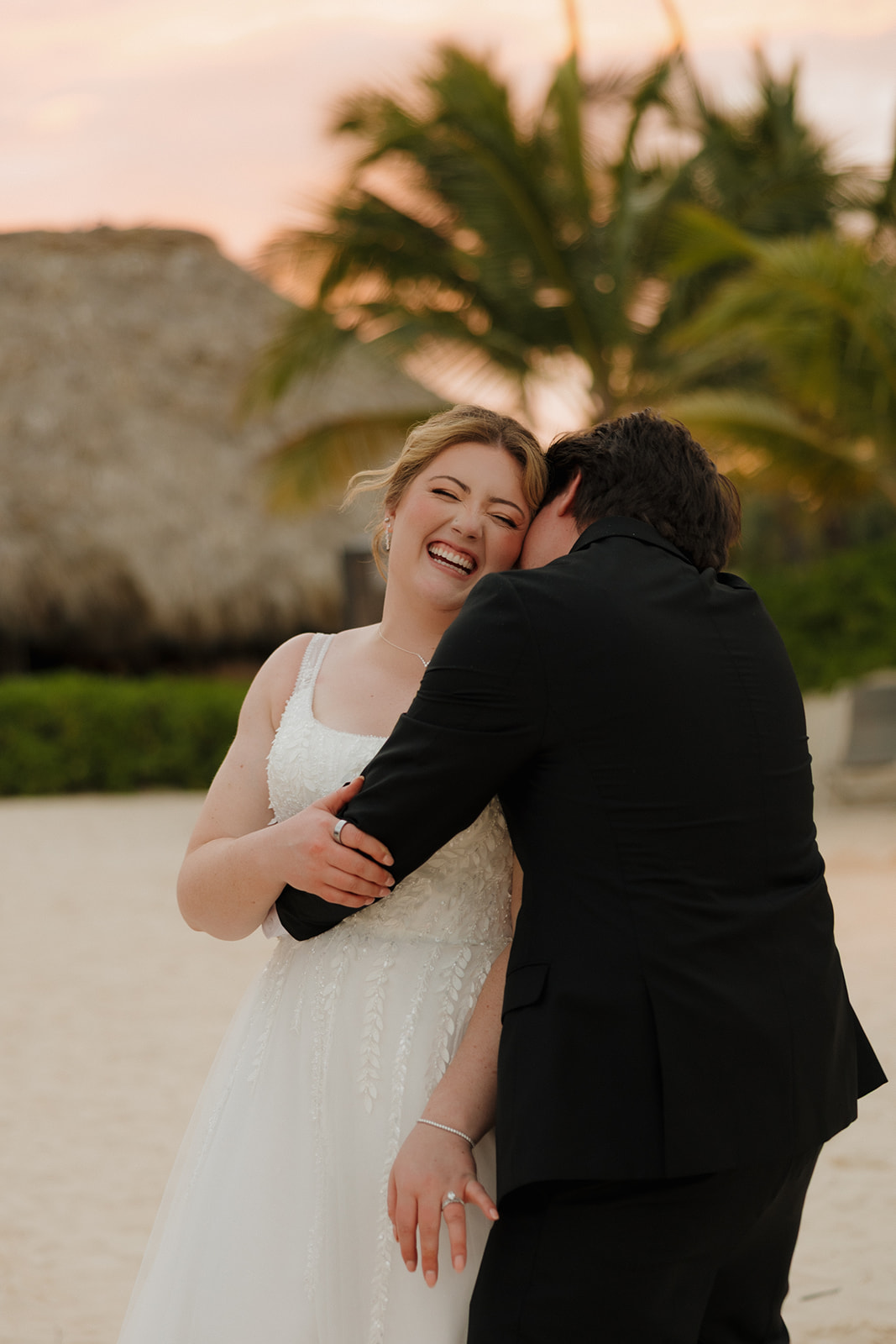 Bride laughing as groom hugs her during sunset portraits at a wedding in Florida
