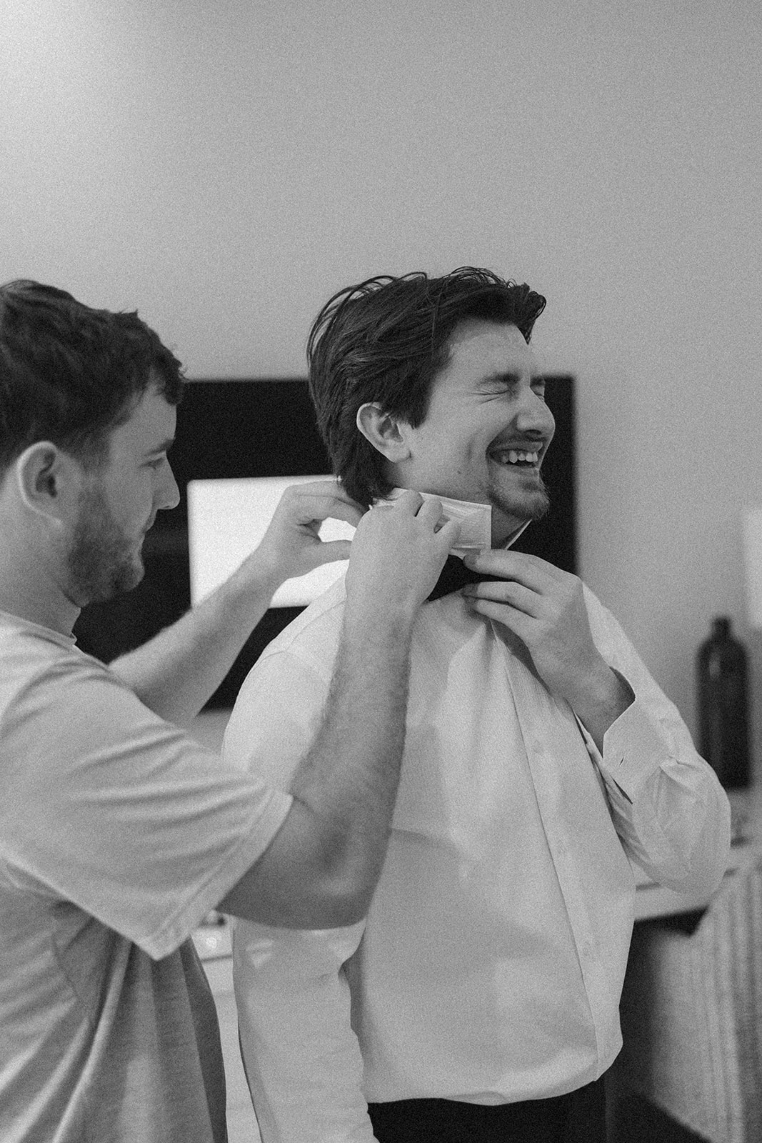 Groom having bow tie adjusted by friend while getting ready for a wedding in Florida