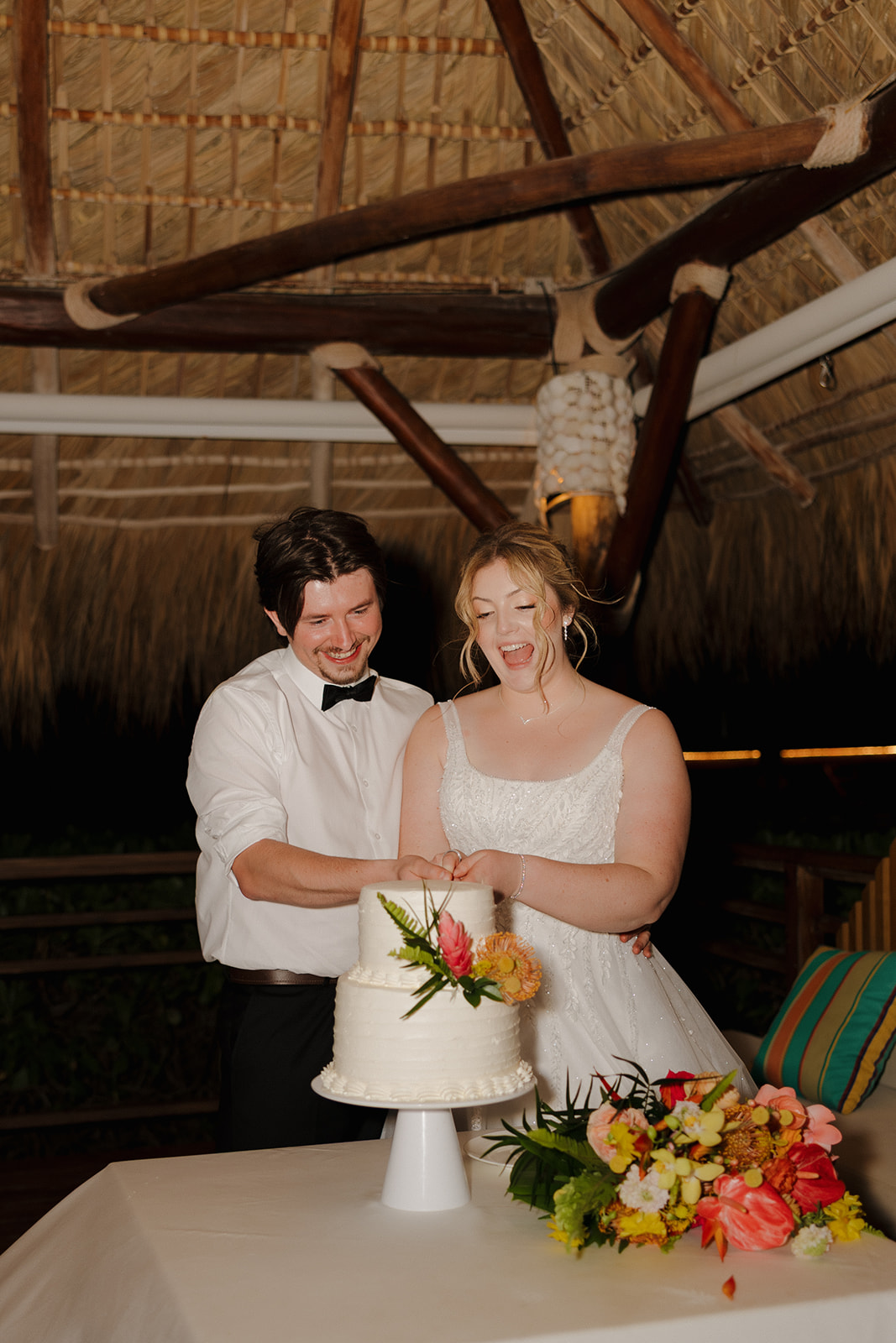 Bride and groom cutting their wedding cake during an evening reception at their Florida beach wedding
