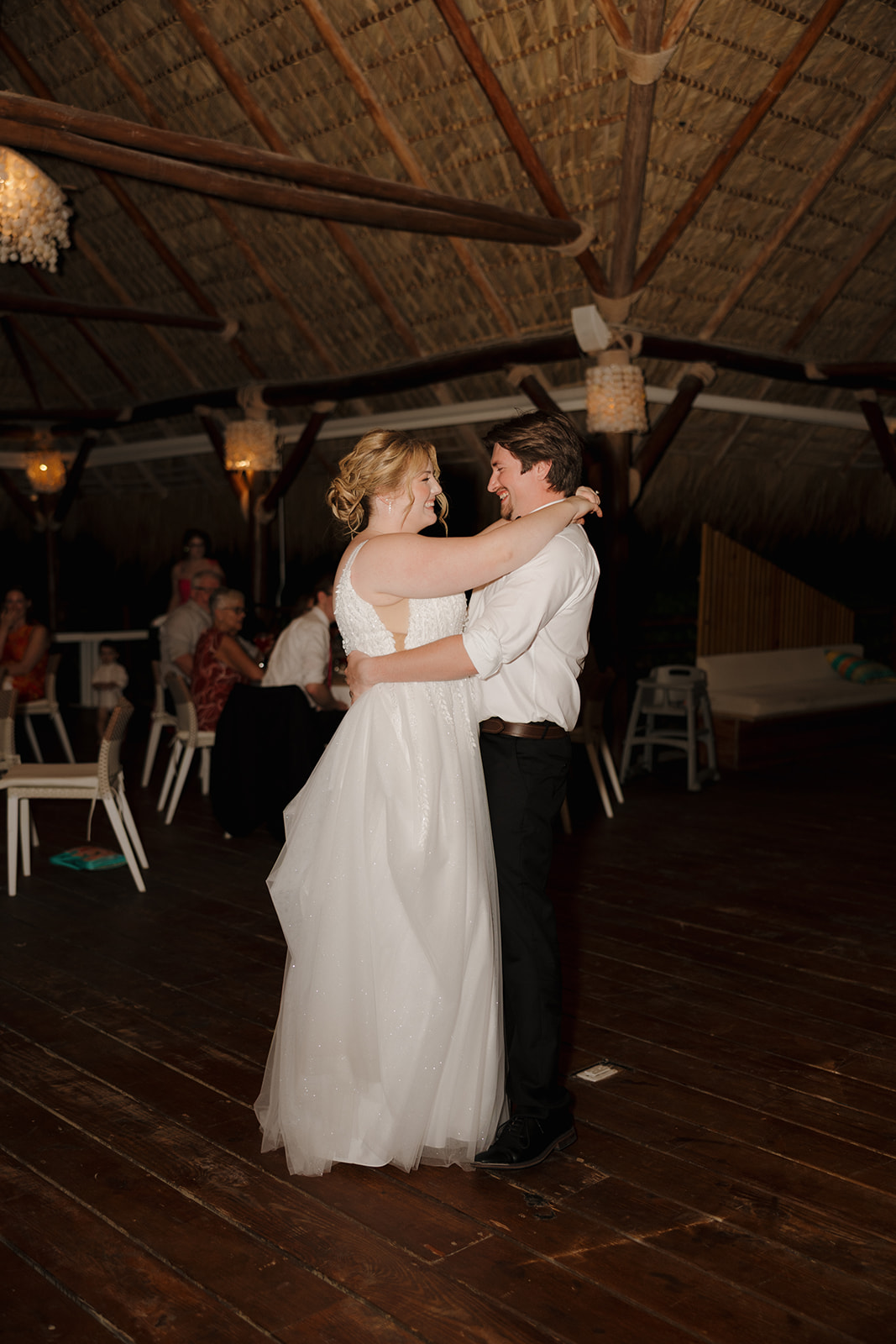 Bride and groom sharing their first dance under a thatched pavilion during their wedding in Florida
